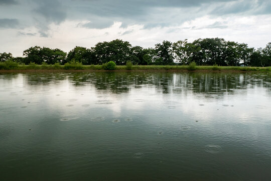 Reflexos da primavera: Gotas de chuva dan&ccedil;am sobre o lago cinzento