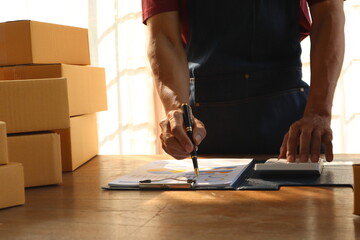 Business man working small businesses from home. utilize smartphones and laptops for various tasks such as commercial checks, online marketing, packing boxes, managing online sales for their SMEs.