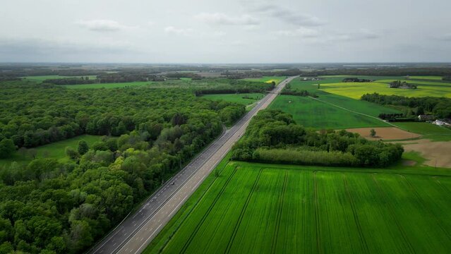 European highway seen from the sky, quiet traffic, in the middle of fields and forests, aerial shooting by drone in France near Paris.