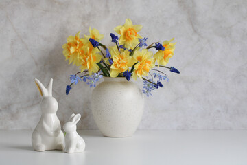 porcelain rabbits on the table and a bouquet of spring garden flowers in a vase. copy space. Easter still life.