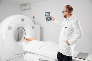 Medical computed tomography or MRI scanner. Doctor holding and examining results of MRI. Woman patient lying on couchette. Concept of medicine, healthcare and modern diagnostics.