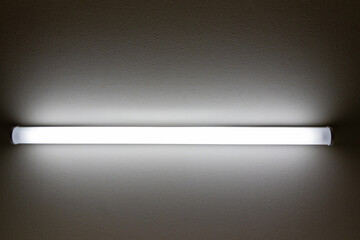 暗い部屋の中で点灯する直管型の照明器具	