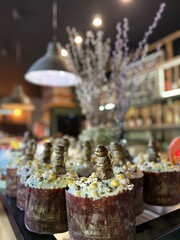 Vertical photo on Orthodox Easter with an Easter cake decorated with white fudge, with a figurine of a bunny and chickens on the table against the background of willow twigs in a bakery