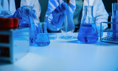 Medical or research scientist or doctor using looking at a test tube of clear solution in a lab or laboratory.