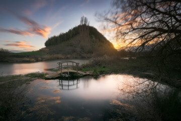 Sunset at the Fuente de la Gallina, in Alar del Rey, Palencia, with the small wooden bridge reflecting in the pond