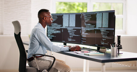 African American Coder Using Computer At Desk