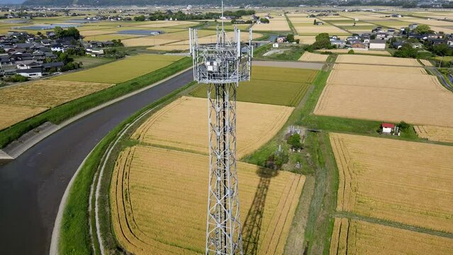 田園風景の中に立つ携帯電話基地局鉄塔　空撮でのパンダウン動画