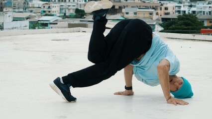 Caucasian B-boy dancer practicing street dancing at rooftop with city or urban. Motion shot of...