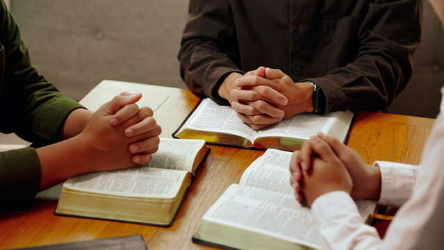 Christian Bible Study Concepts. Christian group or family prayer together with a holy bible on a wooden table in church for worship to god in the morning. people pray with faith, Spirituality.