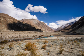 Vibrant view of the Indus River flowing through a barren Himalayan valley under a clear blue sky in Ladakh, India.