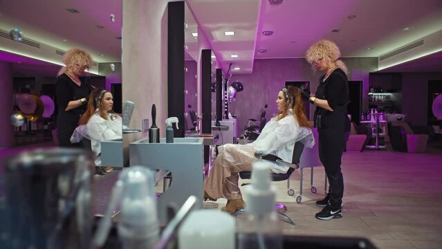 A businesswoman dyes her hair in a beauty salon. A hairdresser applies paint to a girl's hair in, lifestyle care for appearance. High quality 4k footage