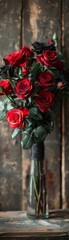 A vase of red roses sits on a wooden table