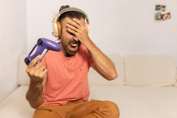 A man in a red shirt is playing a video game and is holding a purple controller