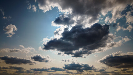 beautiful blue sky with dark dramatic cumulus clouds and sunlight for abstract background