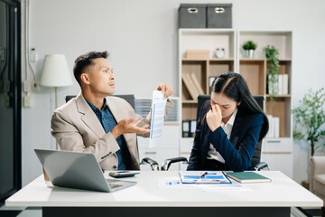 Furious two Asian businesspeople arguing strongly after making a mistake at work in modern office