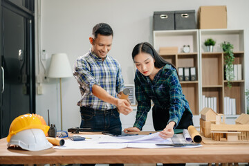 Engineer desk with object paper and tablet with blurry engineer teamwork hardworking to consults about their building project..