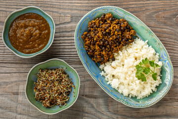 A rice with a dish made of sprouted fenugreek seeds and dried Nepali small peas (sano kerau), on the side alfalfa sprouts and tomatillo chutney in small bowls. Healthy vegan eating concept. 