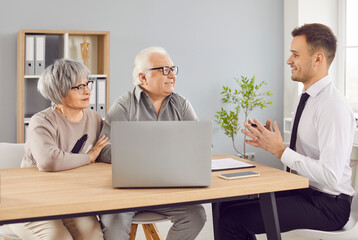 In office realtor advises happy elderly pensioners on real estate purchases. Needs of pensioners broker guides through process decisions align with their pensioners goals and aspirations