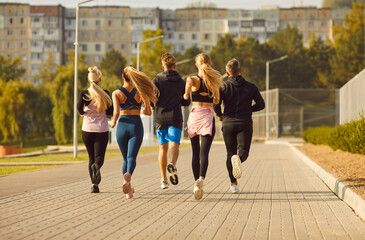 Back side view of a group of sporty people, running and jogging, exercise together in the city park. Team embodies fitness, teamwork, and the joy of an active lifestyle during jog session.