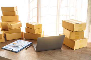 Parcel sme boxes on shelf alongside colorful shopping bags near a laptop on a table. SMEs thriving in online shopping operate from home offices, making packaging a central aspect of their business.