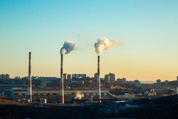 Three pipes from the CHP stand in the background of the city. The pipes release the products of...