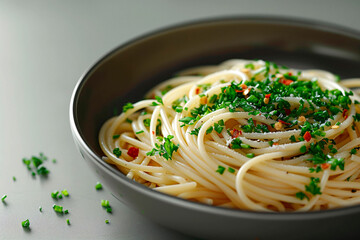 Perfectly cooked spaghetti with a sprinkling of herbs in an elegant grey bowl on a grey background