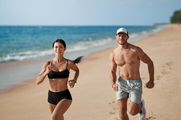 Healthy lifestyle. Jogging outdoors. Young man and woman is running on the sand beach.
