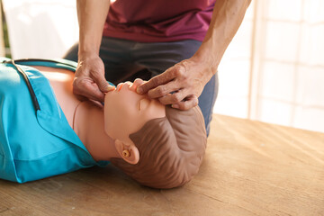 Close-up of middle-aged Asian male hands performing cardiopulmonary resuscitation (CPR) on a...