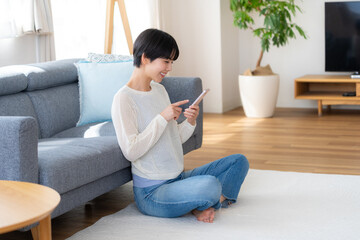 部屋でスマホを操作する女性