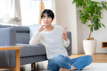 部屋でスマホを操作する女性