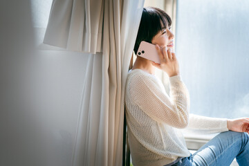 部屋でスマホを操作する女性