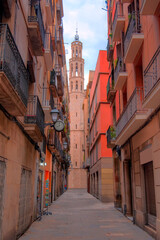 Narrow alley in El Born district,  Santa Maria Del Mar church in the background - Barcelona, Spain 