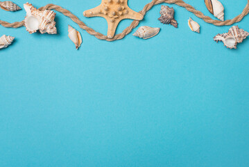 Summer background with seashells, starfish and wave of rope over blue background with copy space....