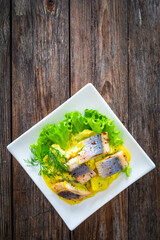 Marinated herring fillets in mustard sauce with dill and lettuce on wooden table
