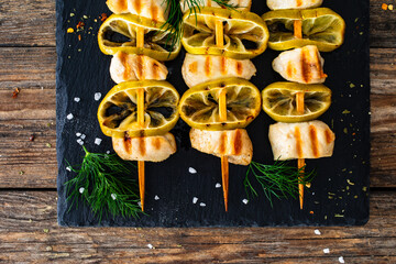 Poultry meat skewers - grilled meat with lime slices on wooden background
