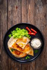 Cheburek - deep-fried turnovers filled with ground meat and vegetables on wooden table
