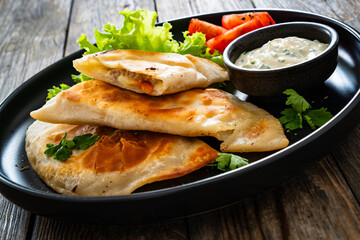 Cheburek - deep-fried turnovers filled with ground meat and vegetables on wooden table
