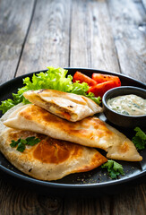 Cheburek - deep-fried turnovers filled with ground meat and vegetables on wooden table
