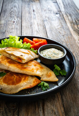Cheburek - deep-fried turnovers filled with ground meat and vegetables on wooden table
