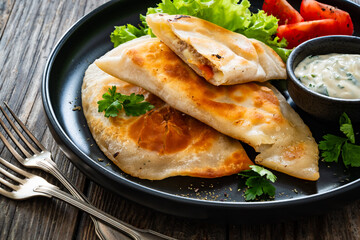 Cheburek - deep-fried turnovers filled with ground meat and vegetables on wooden table
