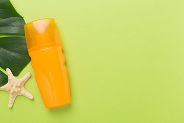 Sunscreen lotion with summer decor on color background, top view