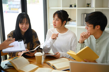 Group of college students sitting around a table in library and discussing research