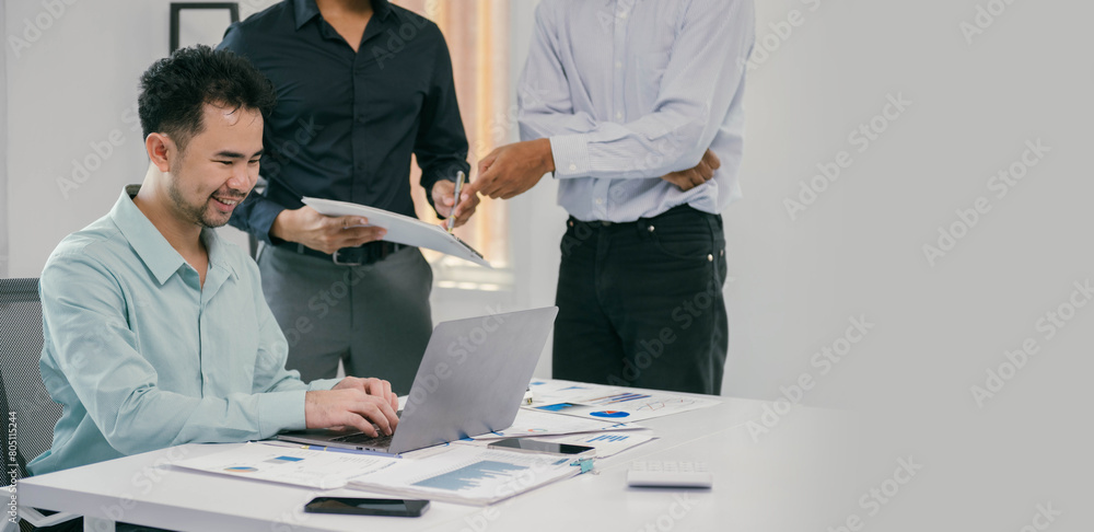 Poster a man is sitting at a desk with a laptop and a stack of papers