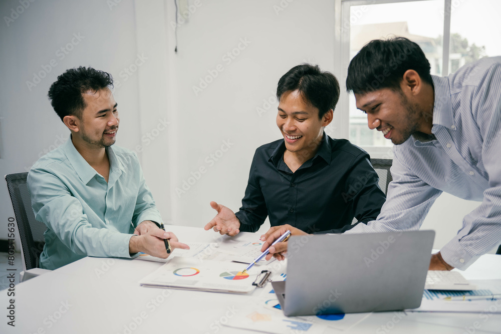 Poster Three men are sitting around a table with a laptop open in front of them