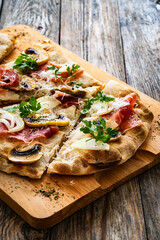 Roman Pinsa with mozzarella cheese, ripening ham and mushrooms on wooden table