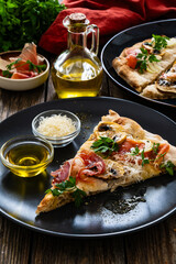 Roman Pinsa slice with mozzarella cheese, ripening ham and mushrooms on wooden table
