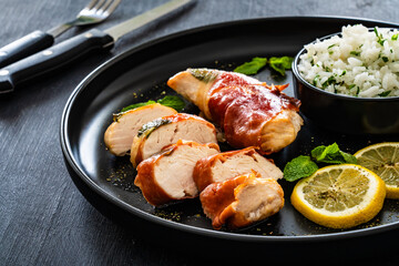 Chicken Saltimbocca - pan-fried chicken cutlets wrapped in Italian prosciutto slices on black...