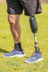 Close up of a man athlete with a prosthesis on his leg standing at the stadium on the field. Back view. Sport concept.
