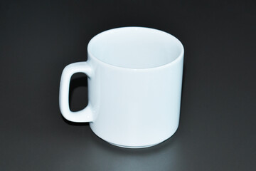 White ceramic mug on a black background. Empty cup for your design.
