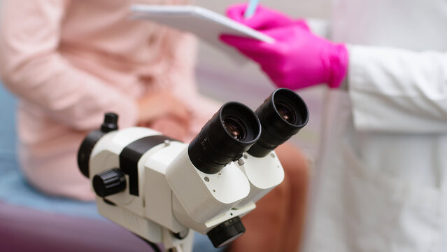Gynecology room in modern clinic. Female gynecologist uses colposcope, takes tests from patient. Woman lies on gynecological chair during colposcopy procedure. Preparation for pregnancy.